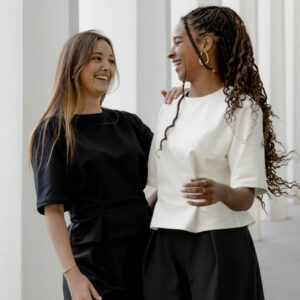 Deux femmes rient ensemble en portant des créations Alibee Couture, exprimant la joie et la complicité à travers la mode.